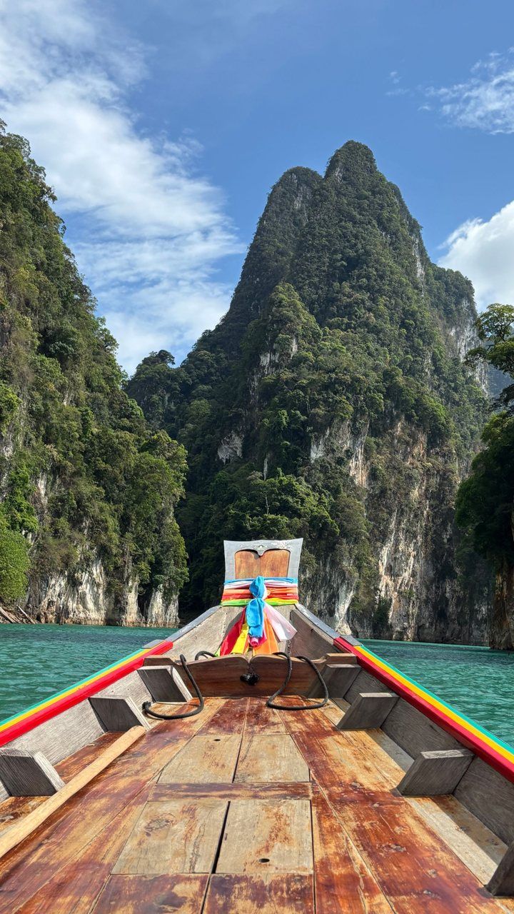 Vertical clip from a longtail boat bow facing limestone cliffs